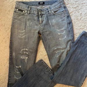 Dolce & Gabbana jeans - Ascoola dolce & gabbana jeans med strass och slitningar. Lågmidjade och bootcut. Lite trasiga i märket bak. Jag är 178 cm och brukar ha s. Har ”sytt in” ett band i midjan så man kan snöra åt de. Går att ta bort, kan skicka bild på hur de ser ut. Syns ej.