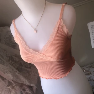 Spets Topp - Superfin spets topp i en slags rosa-orange färg. Små gulliga blommor i spetsen som går över bysten. Lite starkare färg än på bild. Köpt på H&M divided för ca två år sen så osäker på om den fortfarande går att få tag på så därför nypris:) Läs gärna Bio<3