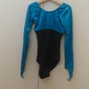 Gymnastikdräkt  - En tävlingsdräkt som är i bra skick med fina detaljer i sammet, dräkten är långarmad och små hål där man ska ha sona pekfingrar. Dräkten passar en tjej som är 10-12år eller har storleken 140-150. 