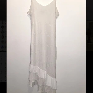 Asymmetrisk vit klänning  - Så så snygg klänning som är asymmetrisk med volanger ner till. 