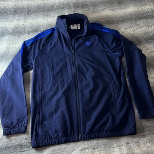 Adidas DIF Vindjacka - Använd några gånger. Bra skick. Har inbyggd luva i kragen. Alltid Oavsett broderat i nacken 