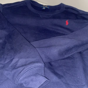 Ralph lauren tjocktröja  - Säljer pågrund av att jag inte använder den.Tröjan är i jätte fint skick och storlek 14-16(jag är 13 och passar den galant.orginalpris: c 1000 .Tröjan är mörkblå med rött märke.Köppt på bozt 