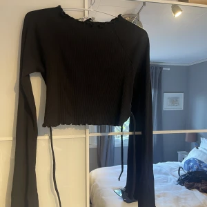 Svart topp - Superfin ribbad långärmad tröja från NA-KD, den är öppen i ryggen och knyts med snören, storleken är xxs men passar nog xs/s också   Köpare står för frakt <3