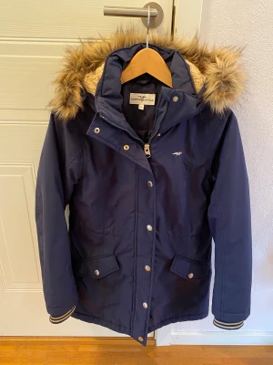 Mörkblå vinterjacka stl 158 - Mörkblå vinterjacka med gulddetaljer till tjej. Storlek 158 från Hampton Republic.