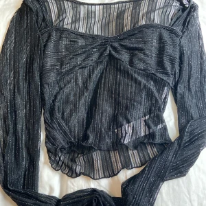 Oanvänd tröja - Helt oanvänd tröja med lapp kvar! Genomskinlig svart med silver detaljer. Perfekt som en cool party topp! Originalpris är 69 kr! 