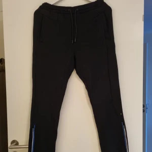 Hugo boss mjukisbyxor - Svarta mjukisbyxor med blå/vita detaljer. En bakficka. Fint skick. Finns tillhörande hoodie.