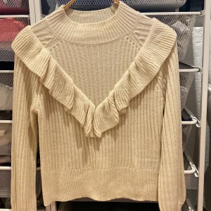 Stickad tröja  - En beige stickad tröja med fina volanger i storlek XS men passar mig som har S. Kom privat för fler bilder. 
