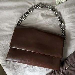 Brun Väska - Säljer en så fin väska som köptes i en butik i Polen. Väskan är aldrig använd. Medföljer ett lång läderband så att man även kan ha väskan runt sig. Nypris: 800kr. Hör av er vid frågor.