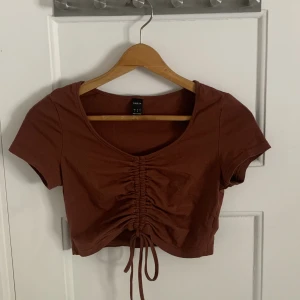 Brun top - Säljer denna väldigt fina toppen från SHEIN med knytdetalj i fram som går att ändra om man skulle vilja. Väldigt bra skick och sparsamt använd.