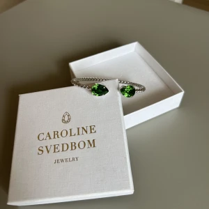 Armband (Mini drop bracelet) - Ett silvrigt armband med gröna stenar från Caroline Svedbom, sparsamt använd. Säljer detta då jag bara använder guldsmycken. 