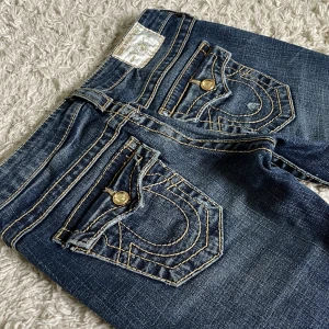 True Religion jeans - True Religion jeans i smått bootcut/straight och lågmidjad modell. ❤️Har jättefina gulddetaljer & diamanter, även guldiga stygn. Är 165cm, innerbenslängd: 76,5, midjemått: 35 tvärs över. Håll koll på min profil, lägger för det mesta upp vintage jeans! 🫶