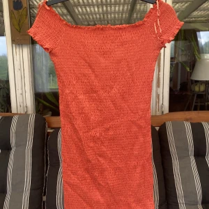 Offshoulder klänning - En offshoulder klänning i aprikos färg. Tight i modellen och sitter väldigt smickrande på med det ”ryschade” tyget.  Har dock aldrig blivit använd av mig då det är lite fel färg för min smak. 