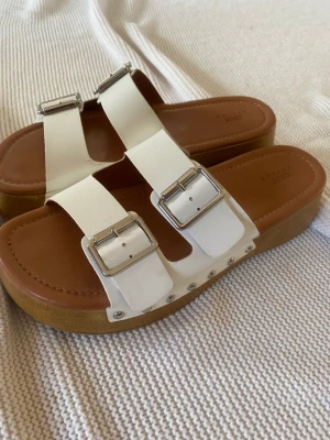 Platå sko - Vita stilrena coola tofflor. Knappt använda. Väldigt fina med silver detaljer på sidan. 