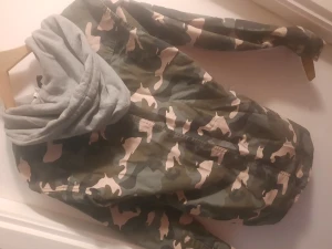 Jacka med militärmönster. - Rosa, grön och grå. Luvan är av samma material som en hoodie luva.  Knappar och inte dragkedja. Lägg eget bud (priset är bara ett försla