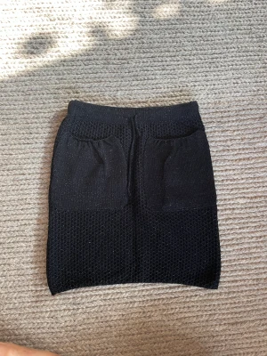 Glittrig kjol - Oanvänd stickad kjol. Svart och glittrig med två fickor på framsidan. Perfekt skick