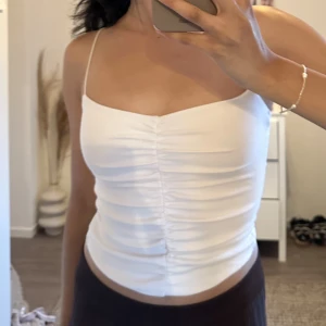 En vit topp med tunna axelband🤍 - Ett vitt linne med tunna axelband🤍 ruched detalj! 