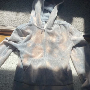 Juicy couture hoodie grå - Grå juicy couture hoodie, tyvärr har den blivit missfärgad i tvätten och fått oranga cirklar men det ser fint ut och coolt, annars är det bra skick!❤️