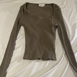 Gina topp - En brungrön oliv tröja med speciell urringning, aldrig använd, inga defekter