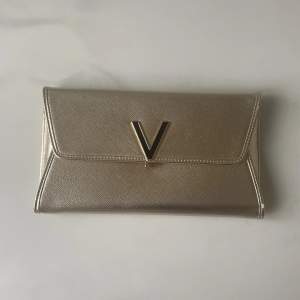 Väska från Valentino by MarioValentino i guld/champagnefärg. Kan bäras som kuvertväska eller på axeln/crossover med medföljande kedja. Väskan är endast använd en - två gånger så är som ny.