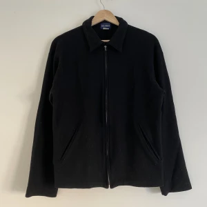 Beams svart zipup - En snygg svart zipup från Beams. Har en rätt så boxy passform och är lite cropped kring midjan. Är väldigt tunn så är inte så varm/tung att bära på.  Rätt så bra skick. Gjord av ull, lite nopprig bara.   Frän o fräsch liksom😎