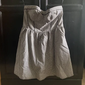 Klänning - Knappt använd klänning utan ärmar. Dragskedjan på sidan av klänningen är sönder :( Den är vit och svart rutig, gråaktig. Den är storlek M men kan sitta lite tight.