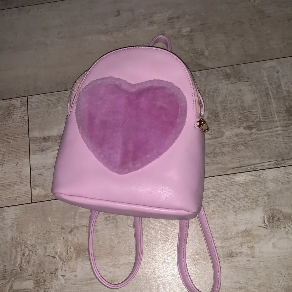 Jättegullig väska med ett hjärta på som är fluffig! Väskan är lite mindre i storleken vilket gör den enkel att ha med sig💕Använd men inga synliga defekter:) Skriv ifall ni har ngr frågor🩷. Väskor.