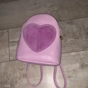 Jättegullig väska med ett hjärta på som är fluffig! Väskan är lite mindre i storleken vilket gör den enkel att ha med sig💕Använd men inga synliga defekter:) Skriv ifall ni har ngr frågor🩷