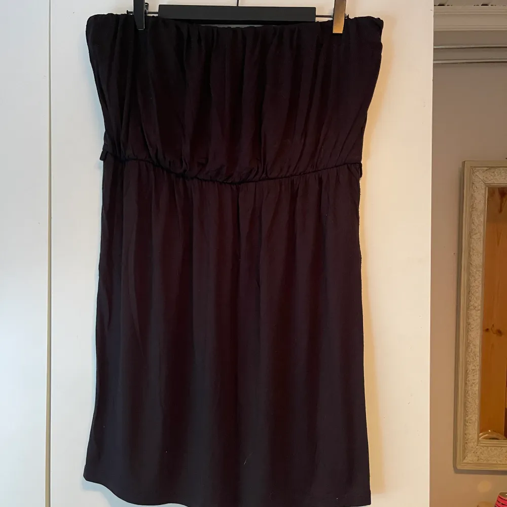 En axelbandslös svart klänning. Storlek: XL. . Klänningar.