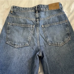 Blåa jeans  - Blåa jeans, breda ben med hål vid knäna. 