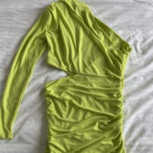 Neongrön enarmad klänning med cutout vid midjan, dragkedja på sidan. Helt oanvänd med prislapp kvar! Storlek L men sitter som en M
