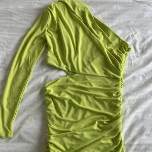 Neongrön enarmad klänning med cutout vid midjan, dragkedja på sidan. Helt oanvänd med prislapp kvar! Storlek L men sitter som en M