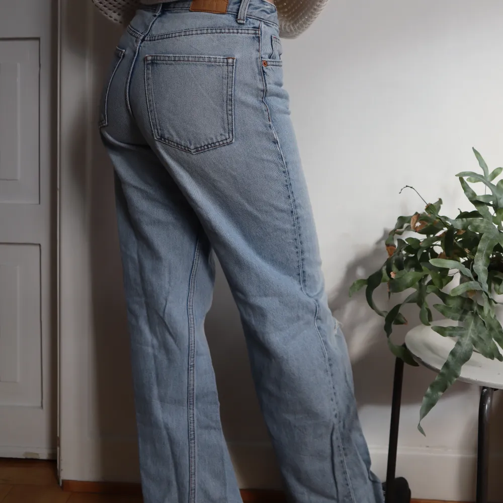 Ljusblåa jeans från Monki. Högmidjade och vida i benen (modellen är 172cm). Har ett snyggt hål som detalj på ena benet. Bra skick! Säljer för jag ej kan ha dom längre 🫧. Jeans & Byxor.