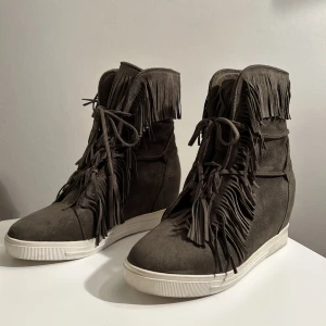 Klackskor med fransar - Otroligt snygga skor med kilklack och fransar, i en khaki / olivgrön färg! Perfa till höst eller vinter och är i ett fint mocka-aktigt material, och är supersköna! I jättebra skick, enda lilla tecknet på användning är på sulan🤍bild 3 är under direktljus💚🤍