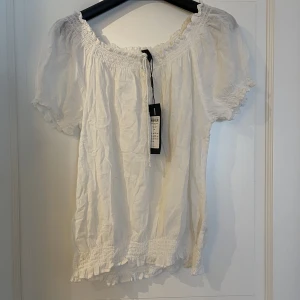 Blus - Tunn blus med resår vid axlarna, man kan ha den både som en t-shirt eller dra ner den över axlarna. I mycket gott skick, den är normalt inte skrynklig. Aldrig använd, ordinarie pris 159kr