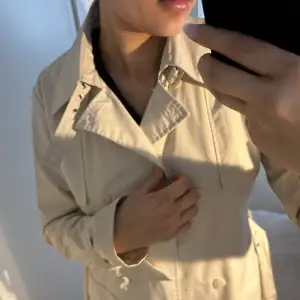 Beige trenchcoat från Vero Moda i storlek 38. Min mammas gamla och därav är storleken lite annorlunda mot dagens. Skulle säga att den passar en S om man vill bara den stängd men även M om man vill ha den öppen. Otroligt fint skick.