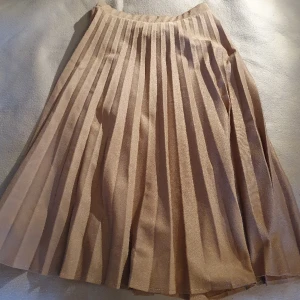 Vintage veckad beige kjol  - Veckad beige / brun kjol i midi-längd. Vintage, var mormors för länge sedan. Står storlek 40 men är liten så passar nog 36-38.