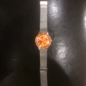 Gant klocka - En orange gant klocka som man kan justera storleken på. Lite repig på glaset, utöver det är den en solklar klocka.