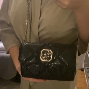 Guess väska - Inga slitningar, ett långt axelband som man kan justera efter hur man vill ha den. Man kan även ha den som midjeväska 