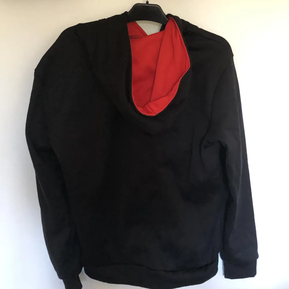Denna hoodie är svart med en röd dragkedja och är röd på insidan av luvan. Vid öppning av dragkedjan är ordet Swag i röda bokstäver. Tröjan är aldrig använd och i nytt skick. Den är i storlek M. . Hoodies.