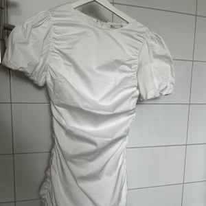 Studentklänning - Klänning med rynkade detaljer, puffärmar, dold dragkedja bak. Använd endast en gång. Fler foton kan skickas vid intresse. 