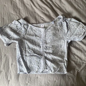 Magtröja - Söt baby blå magtröja med små vita blommor på, från Lindex. Bra skick, stretchig rygg. Kontakta för mer info, och ifall du vill diskutera pris😊