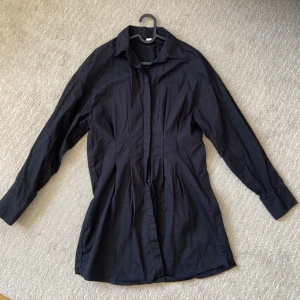Skjortklänning HM - Svart skjortklänning med detaljer vid midjan. Storlek 38. Sparsamt använd 🌟🌸
