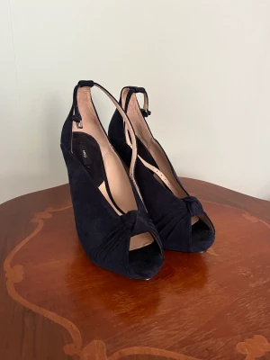 Pumps från Mango, nya. - Pumps från Mango med klack och platå. Mörkblå. Strl 37. Aldrig använda. Spänne runt ankeln.