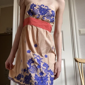 Klänning  - Jättefin off shoulder klänning med så fina blå/lila blommiga detaljer och röda snören så att man kan knyta en rosett i ryggen🫶🏼 Perfekt nu till sommaren⭐️ Klänningen är köpt från märket Flying Tomato🌺