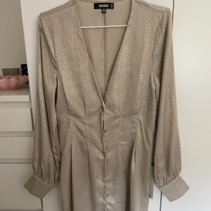 Beige klänning - Så fin klänning med gulddetaljer! Använd en gång så i nyskick. Skriv för bilder hur den ser ut på ☺️