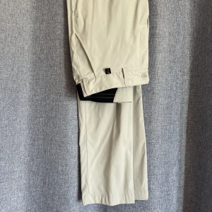 Golfbyxor i stretch - Ett par Peakbyxor i ljust, off white, stretchmaterial. Midjan är resår så passar större och något mindre.   Storleken är 31/34  
