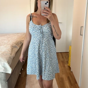 Klänning  - Blommig klänning med knyte vid brösten. Storlek S. 