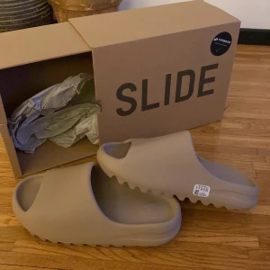 Yeezy slides  - Säljer ett par Yeezy slides begie/puré färg, storlek us 9. Helt nya oanvända säljs pågrund av att dom var fel storlek för mig. Kan snacka om priset