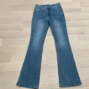 Blåa utsvängda midwaist jeans - Blåa utsvängda blåa jeans, med tryck på fickorna. Bra skick andvända få gånger.