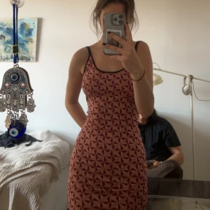 Mönstrad klänning  - Lång tajt klänning med rosa mönster. Klänningen har öppen rygg.